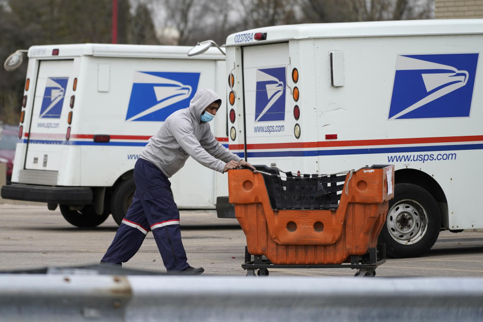 FILE - A United States Postal Service employee works outside a post office in Wheeling, Ill., Dec. 3, 2021. Carriers like the U.S. Postal Service, FedEx and United Parcel Service have capacity to meet projected demand this holiday season, which is cheery news for shippers and shoppers alike. (AP Photo/Nam Y. Huh, File)
