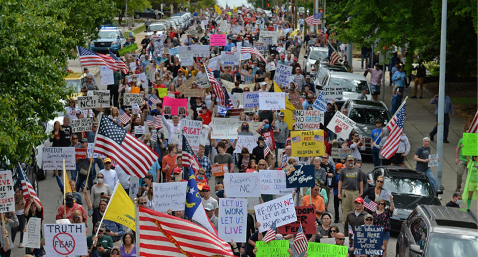 Pictured are over 100 protesters from Reopen NC marching with signs down a North Carolina street.