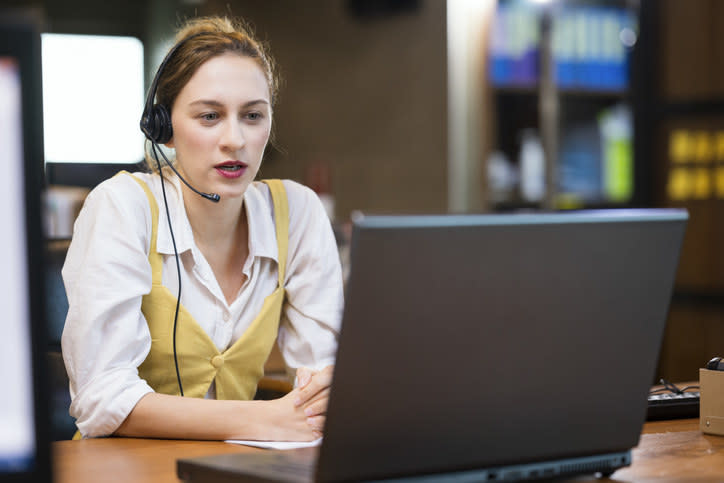 A woman wearing a headset in front of a laptop