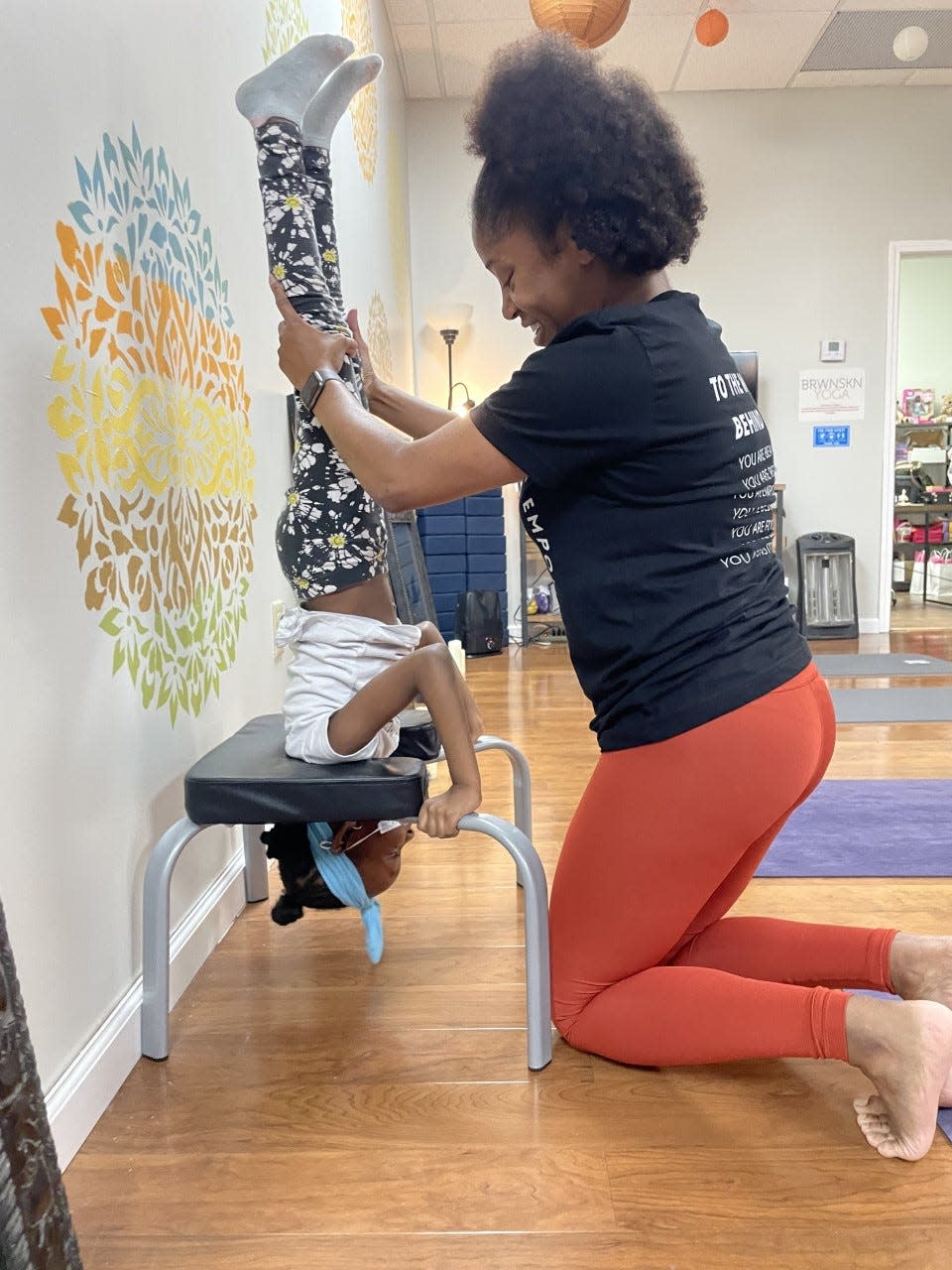 Shawandra Ford, owner of BRWNSKN Yoga in Whitehaven, helps Mareme Diouf learn to do a handstand.