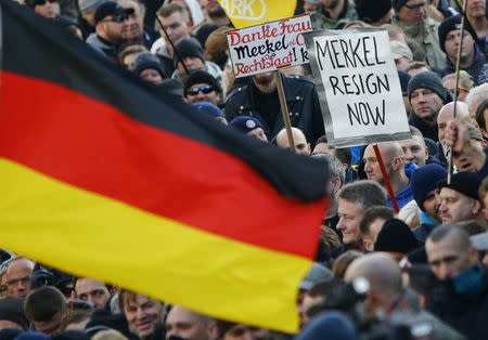 Supporters of anti-immigration right-wing movement PEGIDA (Patriotic Europeans Against the Islamisation of the West) demand the resignation of German Chancellor Angela Merkel on a placard during a demonstration rally in Cologne, Germany. Placard at L reads 'Thank you Merkel and Co. Constitutional state K.O.' Picture taken January 9. 2016. REUTERS/Wolfgang Rattay