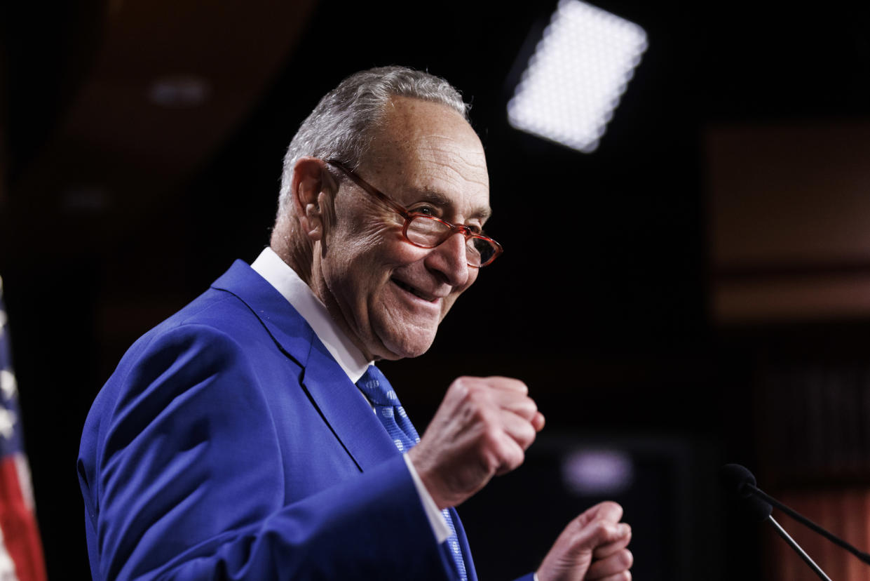 Senate Majority Leader Chuck Schumer standing in front of microphones.