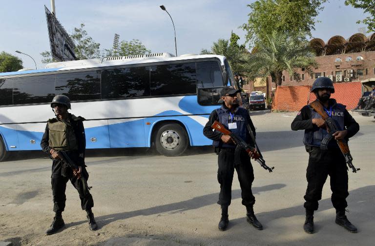 Security personnel stand guard as buses carrying the Zimbabwe and Pakistan cricket teams arrive at the Gaddafi Cricket Stadium in Lahore, northeast Pakistan on May 27, 2015