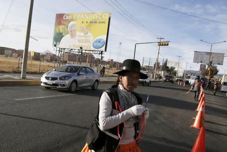 A traffic guard walks past as a bilboard announcing Pope Francis's visit is seen on the side of a road in El Alto July 2, 2015. REUTERS/David Mercado