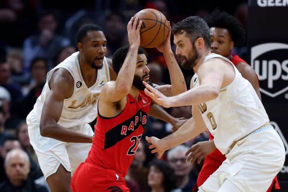 Toronto Raptors guard Fred VanVleet looks to pass the ball from between Cavaliers forward Kevin Love (0) and forward Evan Mobley during the first half Friday, Dec. 23, 2022, in Cleveland.