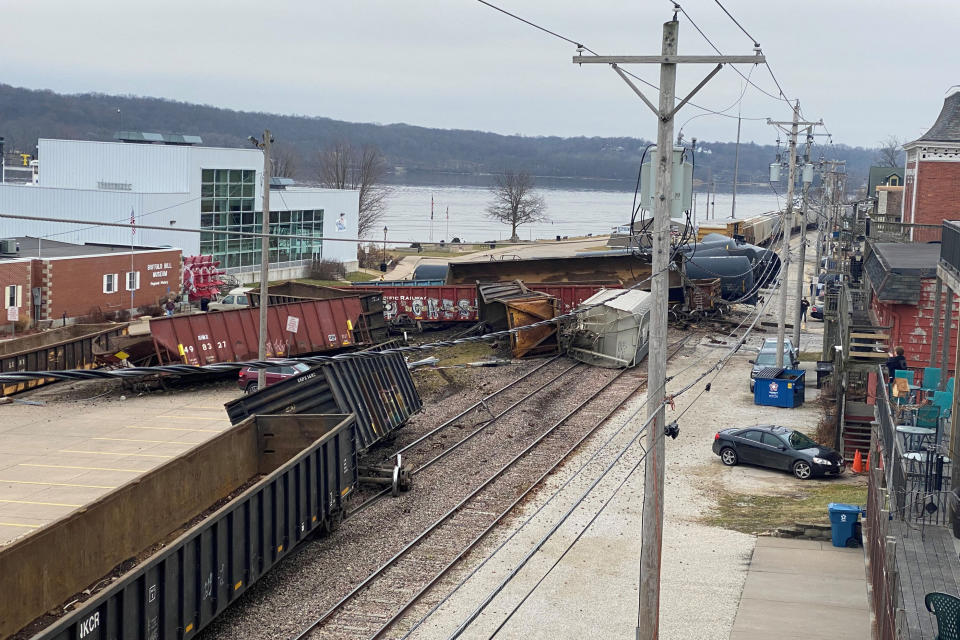 This photo provided by Ryan Burchett of the Mississippi River Drilling Company, shows a train derailment Friday, Jan. 3, 2020, that sent at least a dozen rail cars and tankers off their tracks in downtown LeClaire, Iowa. The derailment forced police to shut down the highway and send a hazardous materials team to the site. (Ryan Burchett/Mississippi River Drilling Co. via AP)