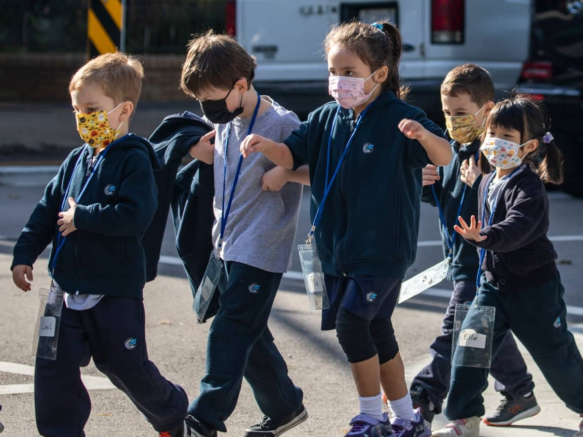 Students in Vancouver, make their way to school wearing protective facemasks in October 2021. Some parents want children to continue wearing masks in the classroom this school year. (Ben Nelms/CBC - image credit)