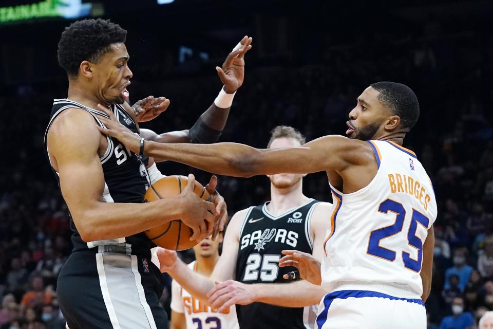 Phoenix Suns forward Mikal Bridges (25) fouls San Antonio Spurs forward Keldon Johnson (3) during the first half of an NBA basketball game Monday, Dec. 6, 2021, in Phoenix. (AP Photo/Ross D. Franklin)