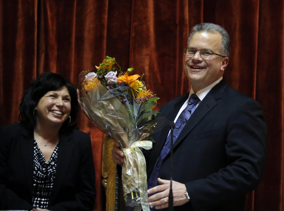 Democrat Nicholas Mattiello, of Cranston, R.I., presents his wife, Mary Ann, with a bouquet of flowers after he was sworn in as the new House Speaker by the Rhode Island House of Representatives at the Statehouse in Providence, Tuesday, March 25, 2014. Mattiello was elected after the abrupt resignation of Gordon Fox, one of the most powerful figures in state government, after his home and Statehouse office were raided as part of a criminal probe. (AP Photo/Elise Amendola)