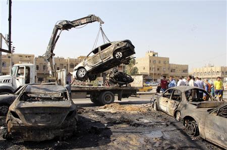 A burnt vehicle is removed from the site of a car bomb attack in Baghdad's al-Shaab district, October 27, 2013. REUTERS/Thaier Al-Sudani