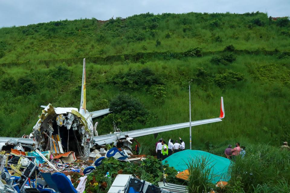 Officials inspect the wreckage of an Air India Express jet at Calicut International Airport in Karipur, Kerala, on August 8, 2020. - Fierce rain and winds lashed a plane carrying 190 people before it crash-landed and tore in two at an airport in southern India, killing at least 18 people and injuring scores more, officials said on August 8. (Photo by Arunchandra BOSE / AFP) (Photo by ARUNCHANDRA BOSE/AFP via Getty Images)