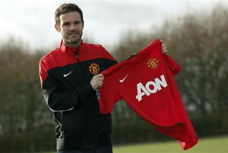 Manchester United's new signing Juan Mata holds a club shirt during a photocall at the club's Carrington training complex in Manchester, northern England, January 27, 2014. REUTERS/Phil Noble