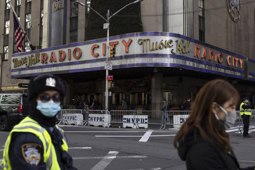 People stand in front of Radio City Music Hall after cancellations of The Rockettes performance due to COVID-19 cases on Friday, Dec. 17, 2021, in New York. New York City had been mostly spared the worst of the big surge in COVID-19 cases that has taken place across the northeastern and midwestern U.S. since Thanksgiving, but the situation has been changing rapidly in recent days. (AP Photo/Yuki Iwamura)