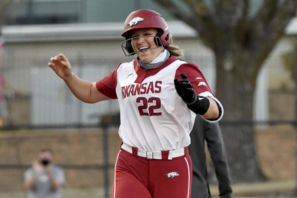 FILE - Arkansas batter Linnie Malkin (22) celebrates as she rounds third base after hitting a two run home run against Mississippi State during an NCAA softball game on Friday, March 26, 2021, in Fayetteville, Ark. Arkansas did something rare during the 2017-18 and 2018-19 seasons: It watched its baseball and softball teams both reach the NCAA tournament. The similarities end there. (AP Photo/Michael Woods, File)