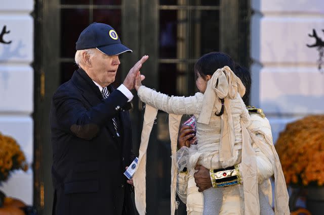 <p>Celal Gunes/Anadolu via Getty </p> Joe Biden with a trick or treater