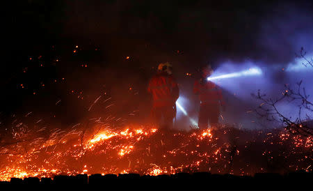 Firefighters tackle a fire on a patch of moorland above the village of Uppermill, Britain, April 22, 2019. REUTERS/Phil Noble