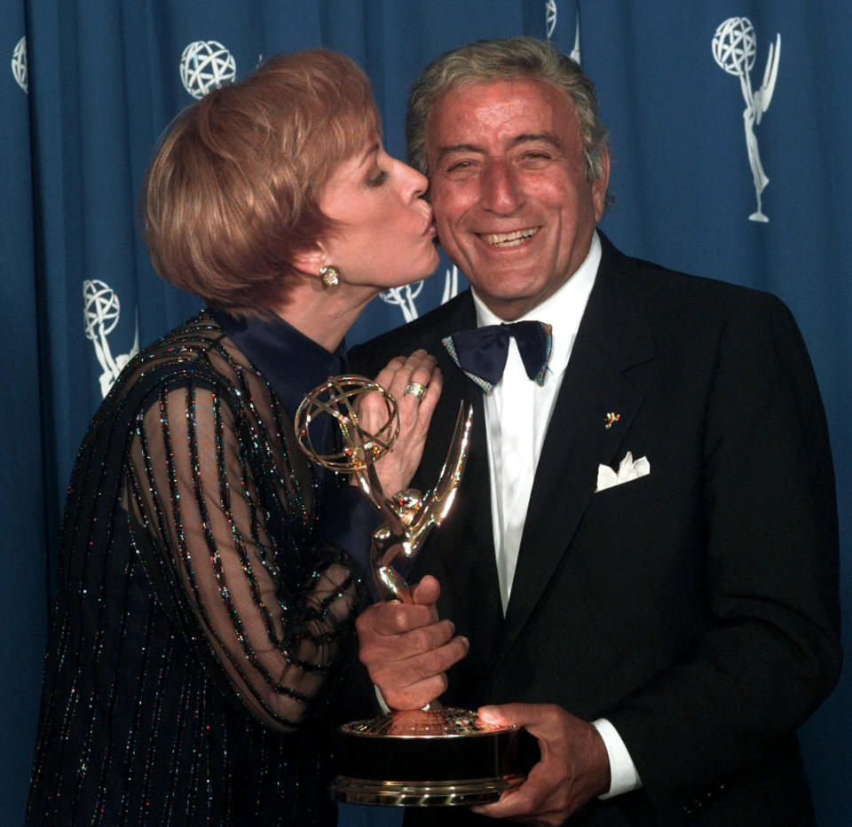FILE - Carol Burnett kisses Tony Bennett after he won an Emmy for outstanding performance for a variety or music program at the 48th Annual Primetime Emmy Awards in Pasadena, Calif., Sunday Sept. 8, 1996. Bennett, the eminent and timeless stylist whose devotion to classic American songs and knack for creating new standards such as "I Left My Heart In San Francisco" graced a decadeslong career that brought him admirers from Frank Sinatra to Lady Gaga, died Friday, July 21, 2023. He was 96. (AP Photo/Mark J. Terrill, File)