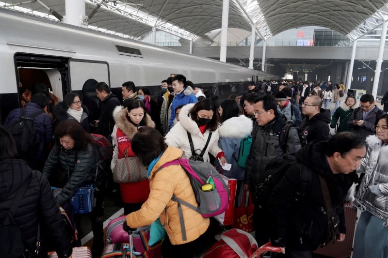 FILE PHOTO: File picture of travellers boarding a train at a railway station in China as the annual Spring Festival travel rush begins ahead of the Chinese Lunar New Year