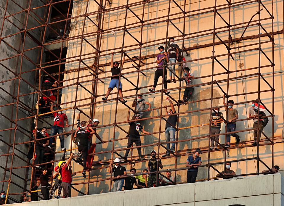 Anti-government protesters climb a building near Tahrir Square during ongoing protests in Baghdad, Iraq, Wednesday, Oct. 30, 2019. (AP Photo/Khalid Mohammed)