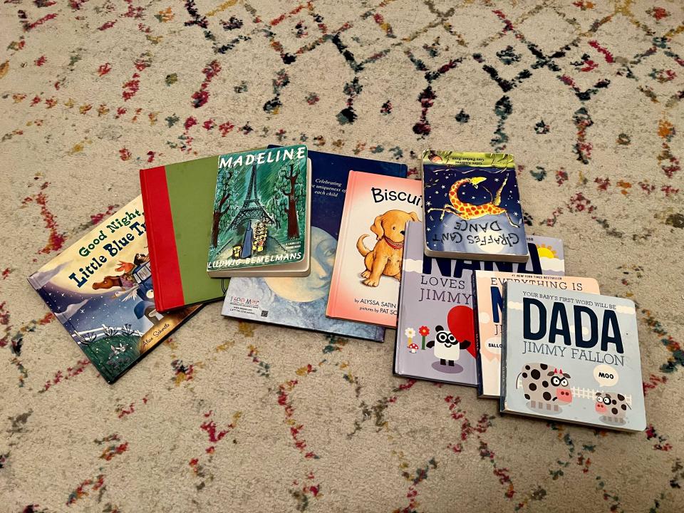 A bunch of children's books on the carpet of a floor.