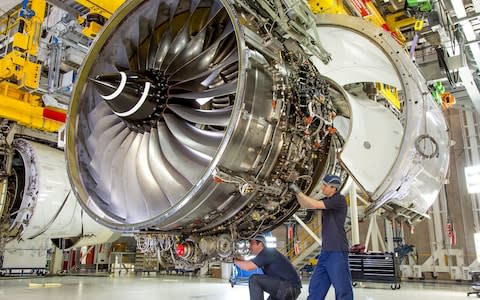 A Rolls Royce engine being worked on by two engineers - Credit: PA