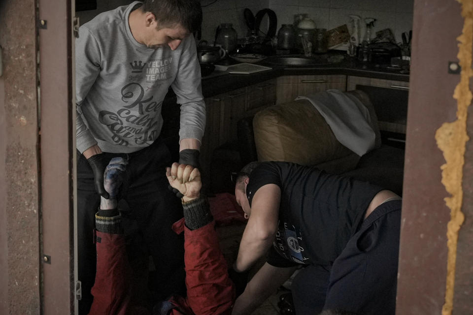 FiLE - Municipal workers remove the body of a man who died from a house in Bucha, Ukraine, Thursday, April 7, 2022. (AP Photo/Vadim Ghirda, File)