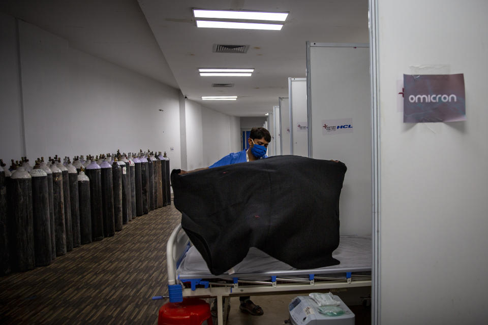 A paramedic make beds at a makeshift COVID-19 care center at an indoor sports stadium in New Delhi, India on Dec. 22, 2021. Caseloads of omicron have remained relatively low in many countries in Asia. For now, many remain insulated from the worst, although the next few months will remain critical. (AP Photo/Altaf Qadri)