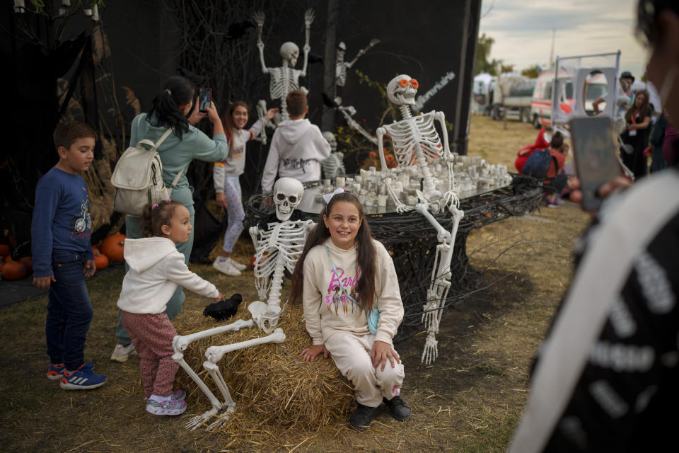 People take pictures with decorations at the entrance of the West Side Hallo Fest, a Halloween festival in Bucharest, Romania, Saturday, Oct. 28, 2023. Tens of thousands streamed last weekend to Bucharest's Angels' Island peninsula for what was the biggest Halloween festival in the Eastern European nation since the fall of Communism. (AP Photo/Andreea Alexandru)