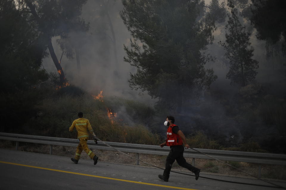 Fire fighters extinguish a forests fire near Kfar Uriya, Thursday, May 23, 2019. Israeli police have ordered the evacuation of several communities in southern and central Israel as wildfires rage amid a major heatwave. (AP Photo/Ariel Schalit)