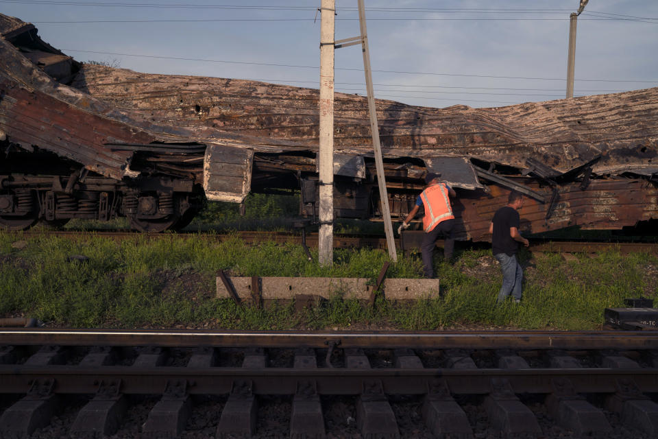 Railway workers verify a heavily damaged train after a Russian attack on a train station Wednesday during Ukraine's Independence Day in the village Chaplyne, Ukraine, Thursday, Aug. 25, 2022. (AP Photo/Leo Correa)