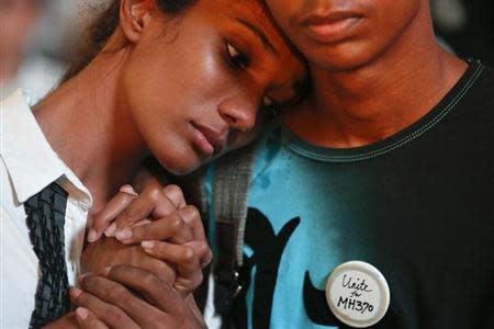 A boy comforts a crying girl during a special prayer for the passengers of the missing Malaysia Airlines flight MH370 in central Kuala Lumpur March 18, 2014. REUTERS/Damir Sagolj