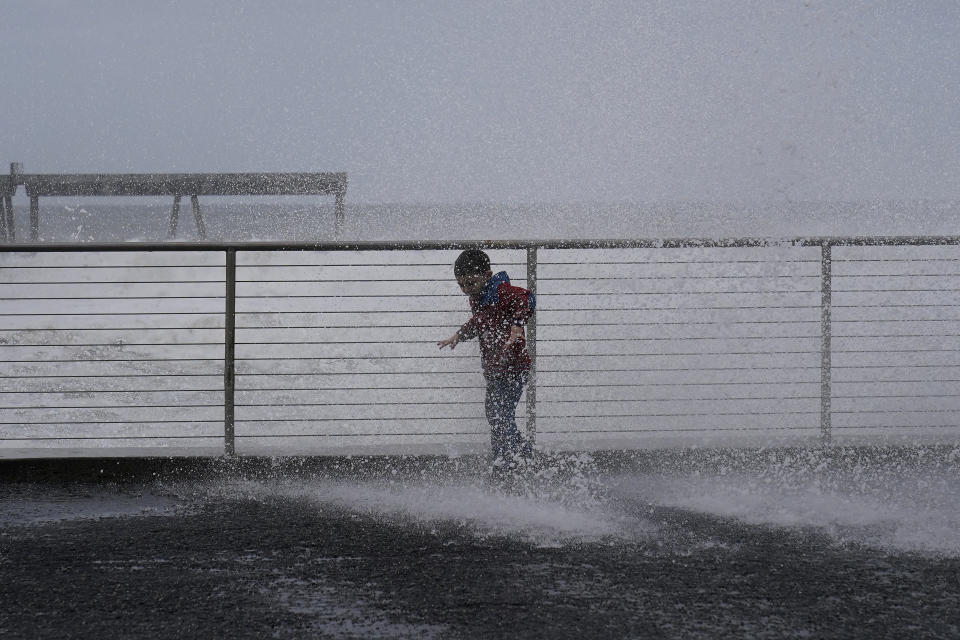 Anthony Tablit, 5, is is soaked as waves crash into a seawall in Pacifica, Calif., Friday, Jan. 6, 2023. California weather calmed Friday but the lull was expected to be brief as more Pacific storms lined up to blast into the state, where successive powerful weather systems have knocked out power to thousands, battered the coastline, flooded streets, toppled trees and caused at least six deaths. (AP Photo/Jeff Chiu)