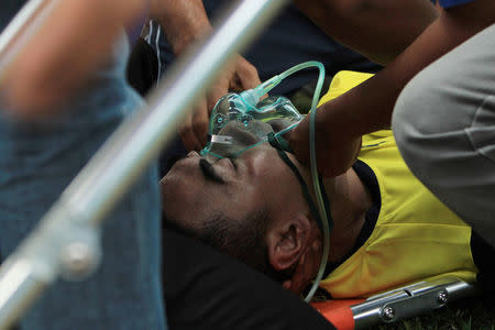 Indonesian goalkeeper Choirul Huda of the Persela Lamongan soccer club receives medical treatment after an injury during a match against Semen Padang soccer club in Lamongan, Indonesia, October 15, 2017. Picture taken October 15, 2017. Antara Foto/Rahbani Syahputra via REUTERS