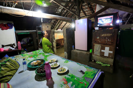 A woman watches TV as seawater hits her house during high tide in Sriwulan village in Demak, Indonesia, January 31, 2018. REUTERS/Beawiharta