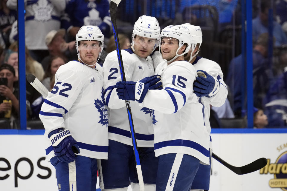 Toronto Maple Leafs defenseman Luke Schenn (2) celebrates his goal against the Tampa Bay Lightning with center Noel Acciari (52) and center Alexander Kerfoot (15) during the first period of an NHL hockey game Tuesday, April 11, 2023, in Tampa, Fla. (AP Photo/Chris O'Meara)