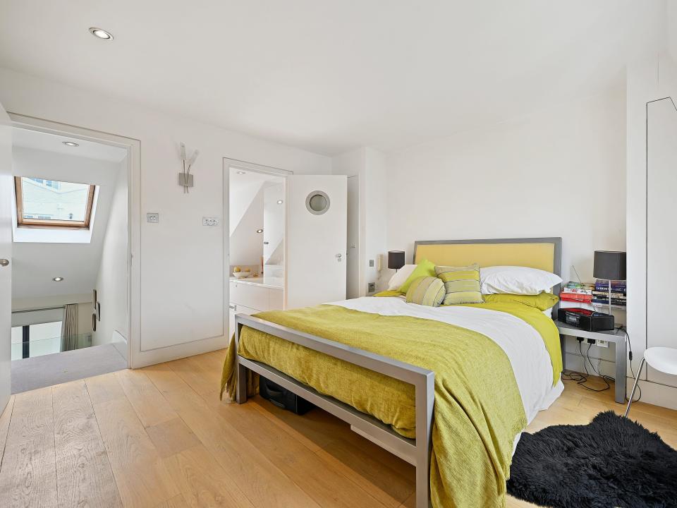 A bedroom with wood floors and a lime green bedspread.