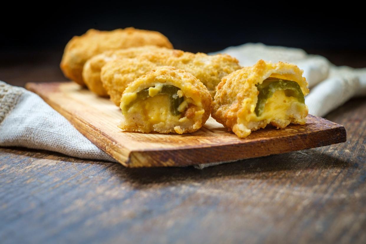 Crispy fried cheddar cheese jalapeno popper bites served on wooden cedar plate with dark moody lighting