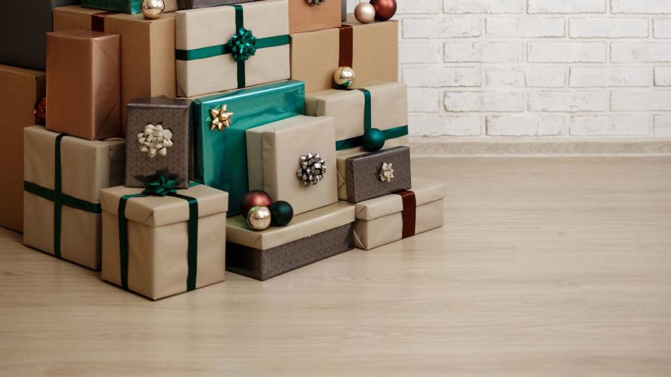 christmas gift boxes laid out in the shape of a christmas tree over white brick wall