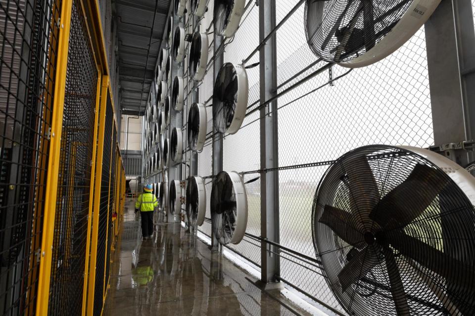 A production technician inside a towering structure with fans