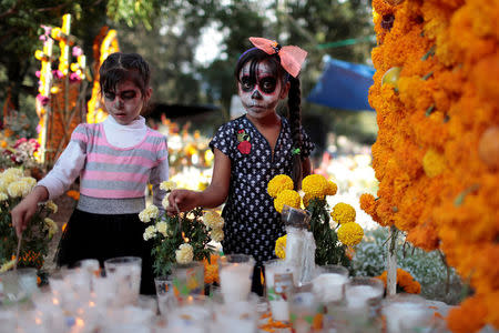 Girls light up votive candles for the grave of their loved one during the Day of the Dead celebrations at a cemetery in Tzintzuntzan, Mexico, November 1, 2017. REUTERS/Alan Ortega