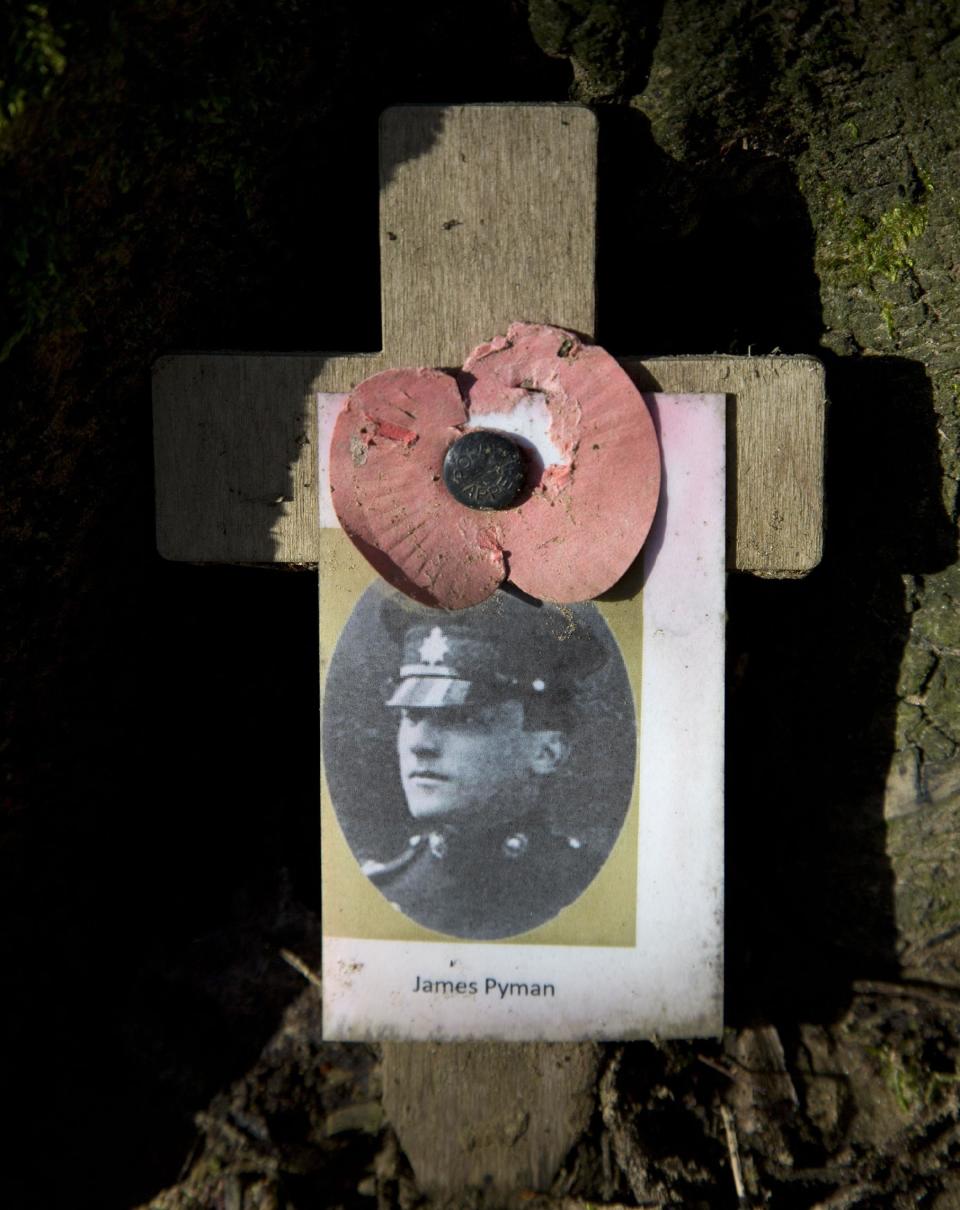 In this photo taken on Feb. 3, 2014, a photo of World War One British soldier Captain James Pyman from the 3rd Battalion Borders Regiment who died on Nov. 18, 1914, is remembered with a wooden cross and a poppy at Hill 62 in Zillebeke, Belgium. Britain's Imperial War Museum is launching an ambitious online database on Monday, May 12, 2014 to remember the lives of the millions of men and women who served in World War One. The museum hopes that the history project, timed to coincide with the 100th anniversary of WWI, could form a permanent digital memorial to the scores of soldiers, nurses and others from Britain and the Commonwealth who contributed to the war by piecing together their life stories. (AP Photo/Virginia Mayo)