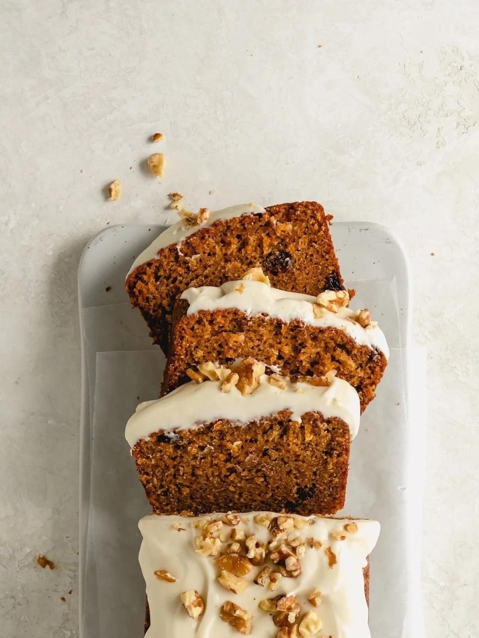 Sliced carrot cake with icing and nuts on plate, top view