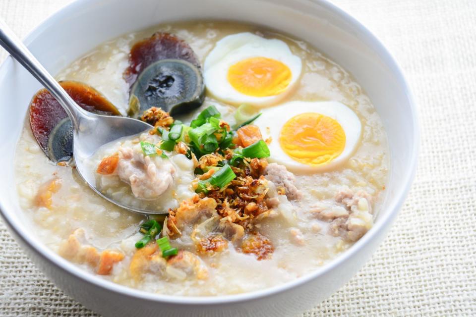 "Congee" wird vor allem in Asien oft zum Frühstück serviert. Dabei handelt es sich um einen bekömmlichen Reisbrei mit Gemüse und Ei. Zunächst wird Reis mit Wasser, Salz und getrockneten Shiitake-Pilzen etwa zwei Stunden auf dem Herd zu einem Brei gekocht. Pochierte oder hart gekochte Eier, Frühlingszwiebeln, Koriander und je nach Geschmack Röstzwiebeln oder Chili runden das Gericht ab. (Bild: iStock/Pinrath Phanpradith)