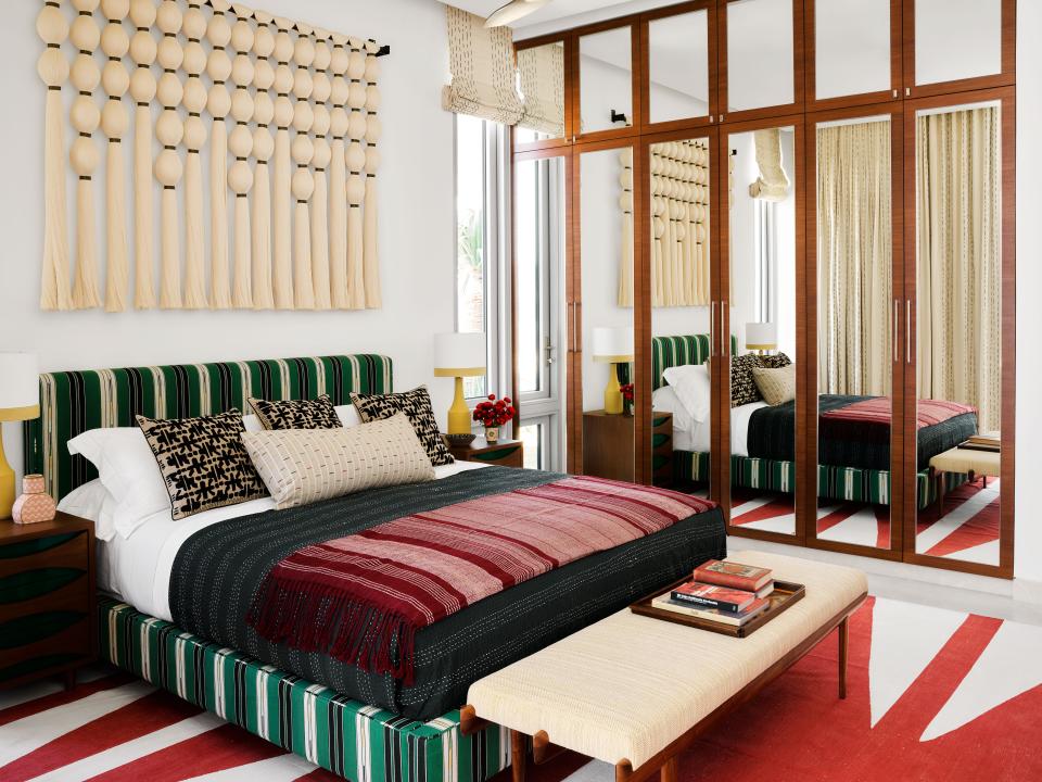 In a guest bedroom, a Pierre Frey cotton stripe covers the bed. Dana John bench; lamps from Lawson-Fenning on Bullard-Designed side tables; custom rug.