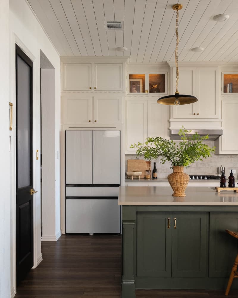 Kitchen with cream top cabinets and green cabinets on kitchen island.