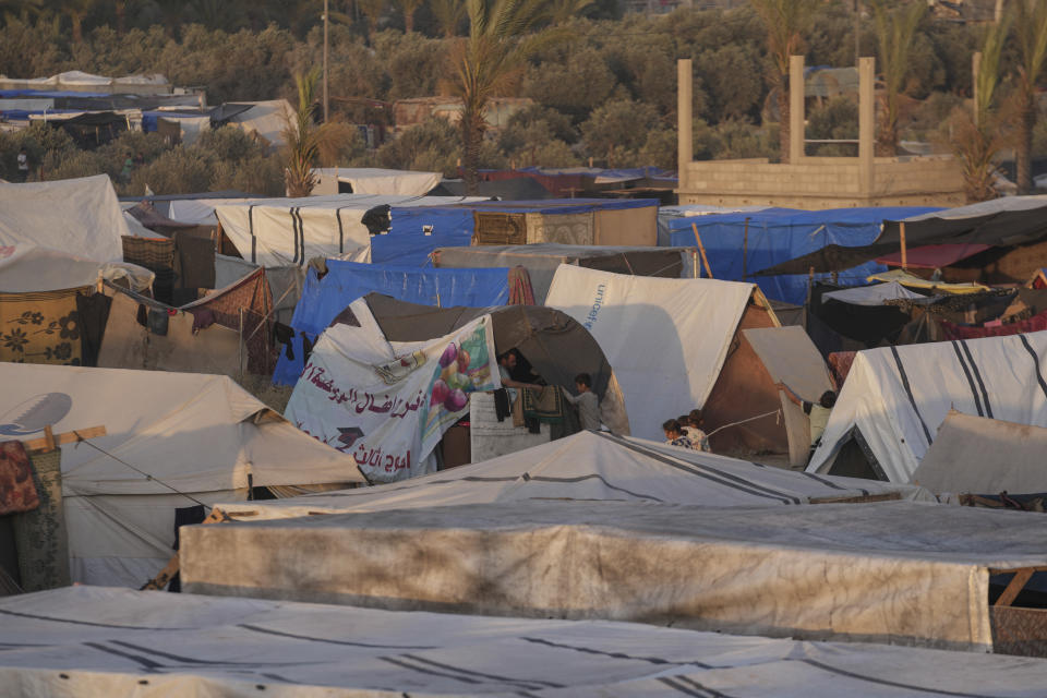 Palestinians displaced, by the Israeli air and ground offensive on the Gaza Strip, stand in a makeshift tent at a camp in Deir al Balah, Monday, May 13, 2024. Palestinians on Wednesday, May 15, 2024, will mark the 76th year of their mass expulsion from what is now Israel. It's an event that is at the core of their national struggle, but in many ways pales in comparison to the calamity now unfolding in Gaza. (AP Photo/Abdel Kareem Hana)