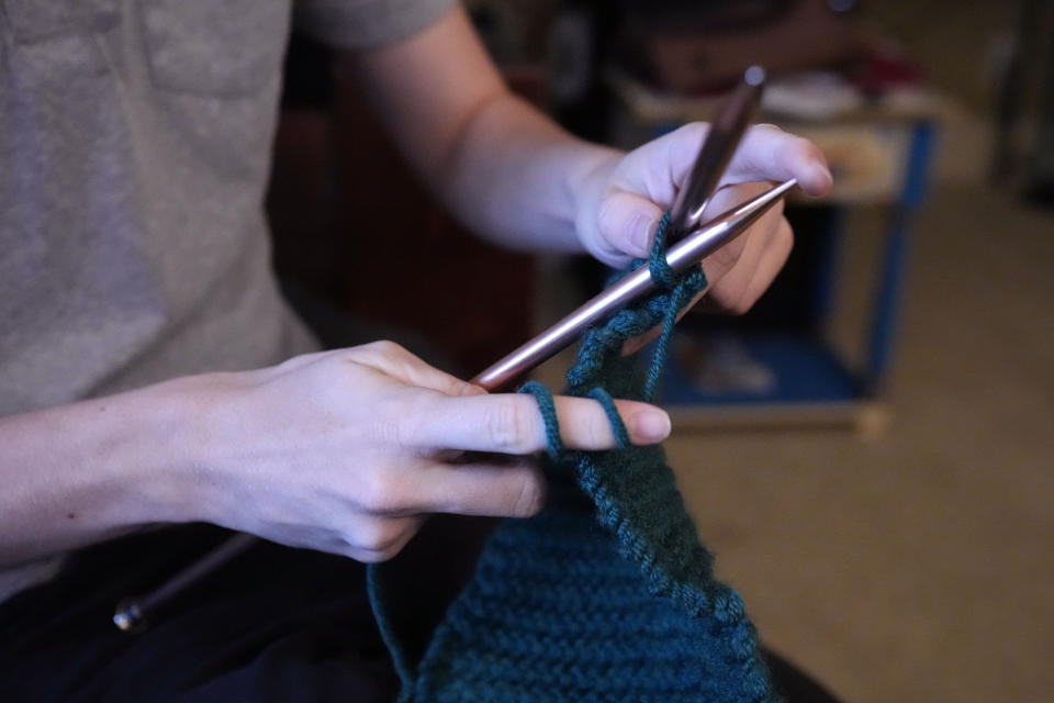 Ray Walker, 17, demonstrates his stitching technique for knitting, one of his hobbies, while speaking about his need to move to Virginia for continued gender-affirming care and the effects on his family, Wednesday, June 28, 2023, in Madison County, Miss. This year, Republican Gov. Tate Reeves signed legislation banning gender-affirming care for anyone younger than 18. (AP Photo/Rogelio V. Solis)