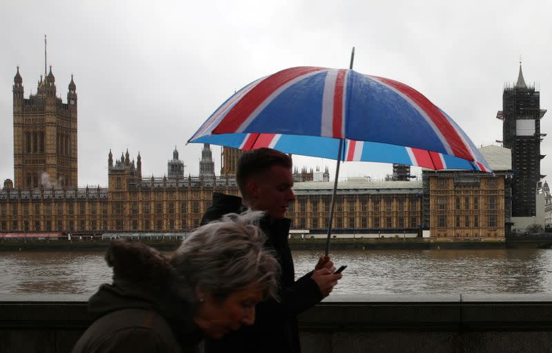 FILE PHOTO: People walk over Westminster Bridge on a rainy day with the Houses of Parliament in the background in London