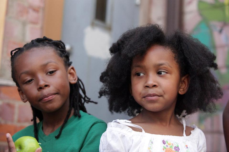 Menelik Swyer, 9, of Detroit, (left) and his sister Naja Swyer, 6, of Detroit enjoy green apples during the National Natural Hair meetup at the Artist Village in Detroit on Saturday, May 19, 2012.  The California State Senate on April 22, 2019 passed a bill that would ban schools and workplaces from having dress codes against braids, twists and other natural hair styles.