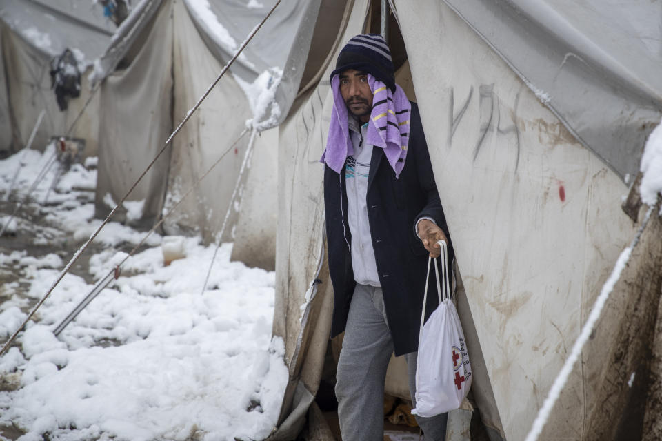 A migrant steps out of a tent at the Vucjak refugee camp outside Bihac, northwestern Bosnia, Tuesday, Dec. 3, 2019. A top European human rights official has demanded immediate closure of a migrant camp in Bosnia where hundreds of people have refused food and water to protest lack of protection in snowy and cold weather. (AP Photo/Darko Bandic)